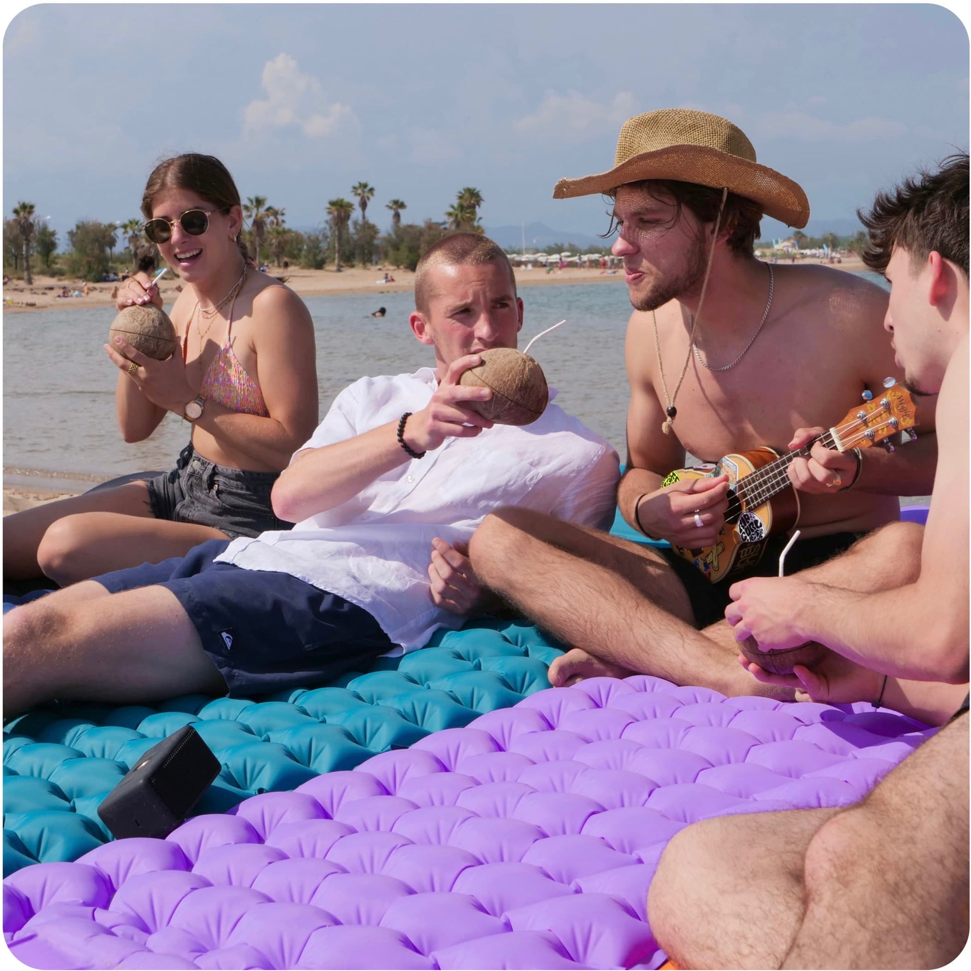 Des amis qui profitent d'un picnic à la plage sur les matelas gonflable coziya